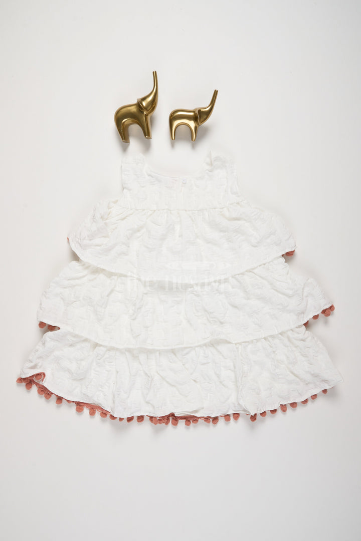 The Nesavu Girls Fancy Frock White-Tiered Girls Fancy Frock with Peach Pom-Pom Trim and Textured Design for Special Occasions Nesavu Nesavu White-Tiered Fancy Frock Girls Peach Pom-Pom Trim Textured Layers Special Events